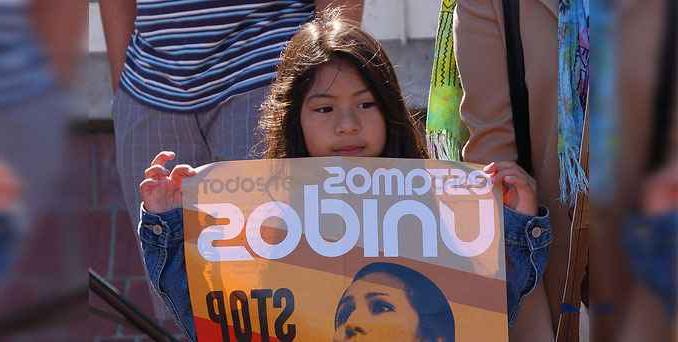 A child holds a sign that says "estamos unidos"